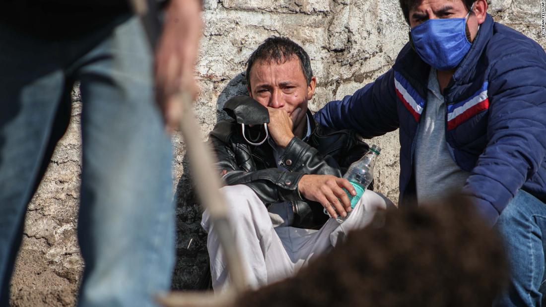 Peruvian migrant Jose Collantes cries as he watches cemetery workers bury his wife, Silvia Cano, in Santiago, Chile, on Friday, July 3. She died of coronavirus complications, according to Collantes.